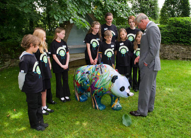 Children standing around a Wild in Art Panda Sculpture with King Charles