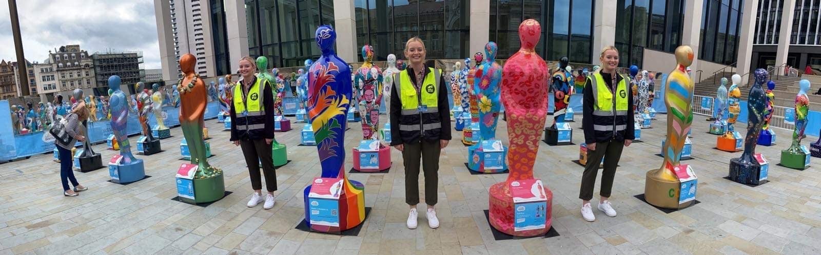 Isy standing between gratitude sculptures