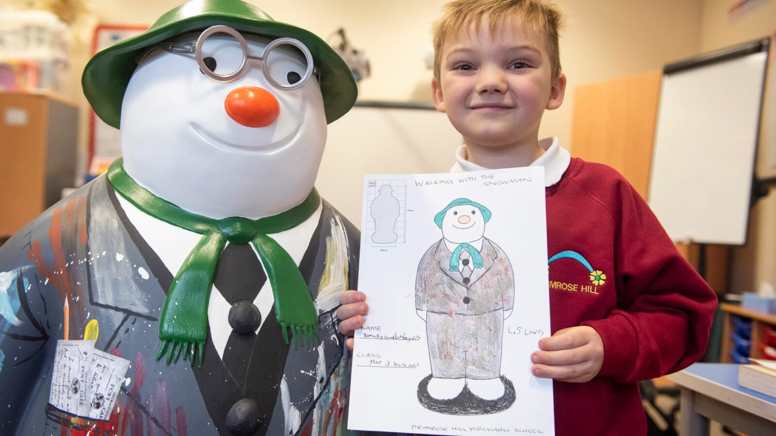 Child posing with his design and the designed Walking with The Snowman sculpture